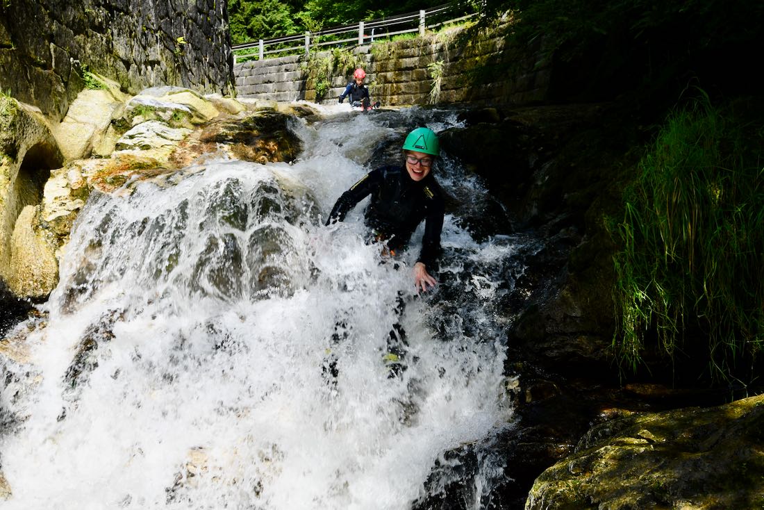 Melanie rutscht die Steine im Bach hinunter beim Family KAT Walk