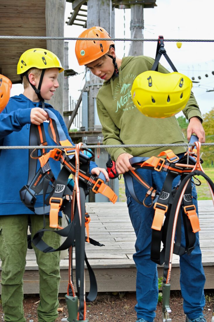 Benni und Flo ziehen Kletterausrüstung an am Bio-Seehotel Zeulenroda im Vogtland