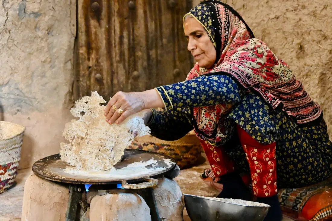 Eine Frau bäckt Brod im Bait Al Safah Museum