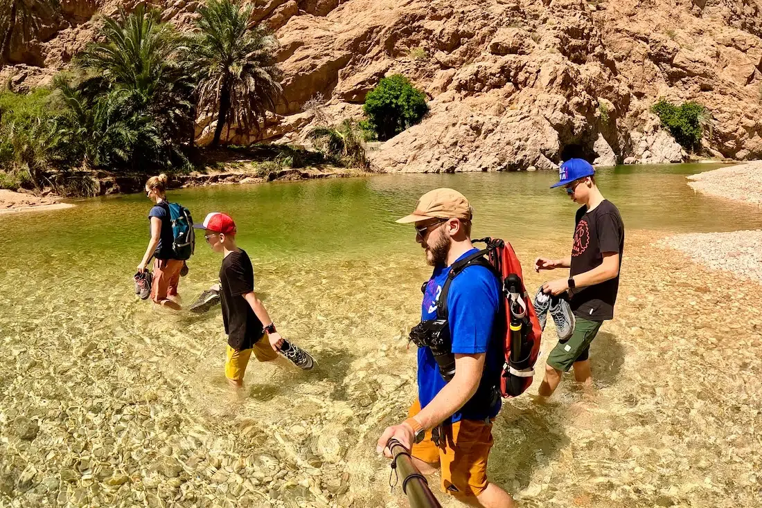 Fravely gehen durch den Fluß im Wadi Shab im Oman
